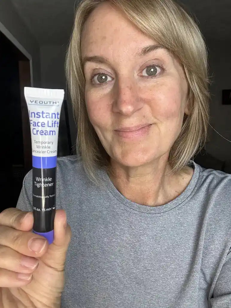 Woman holding a tube of Vothic Instant Face Lift Cream in a casual setting.