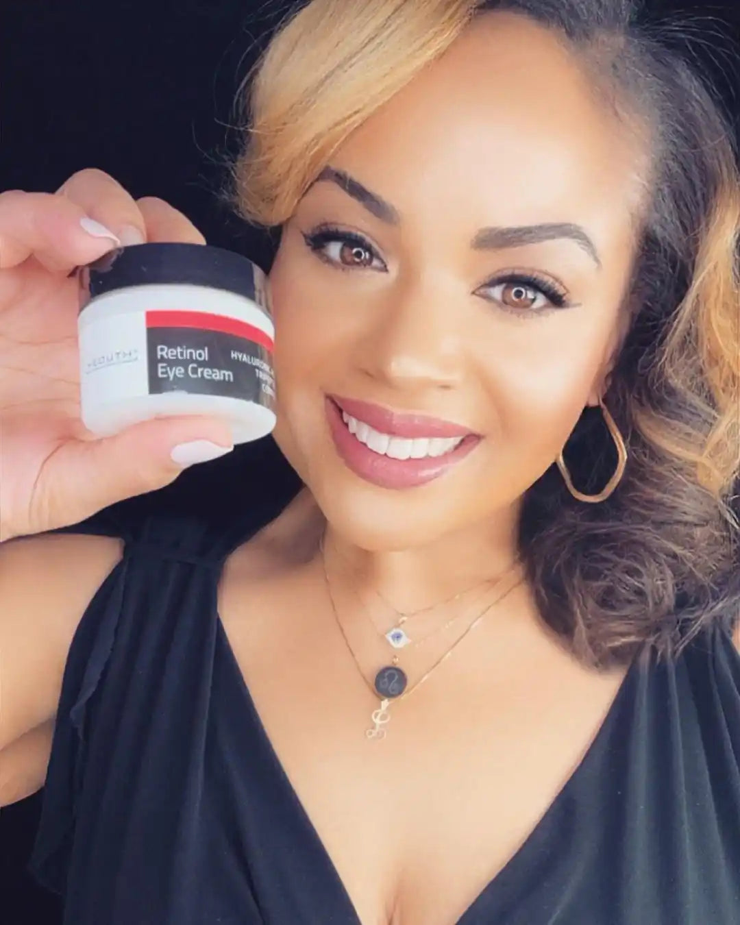 Woman holding a jar of Retinol Eye Cream