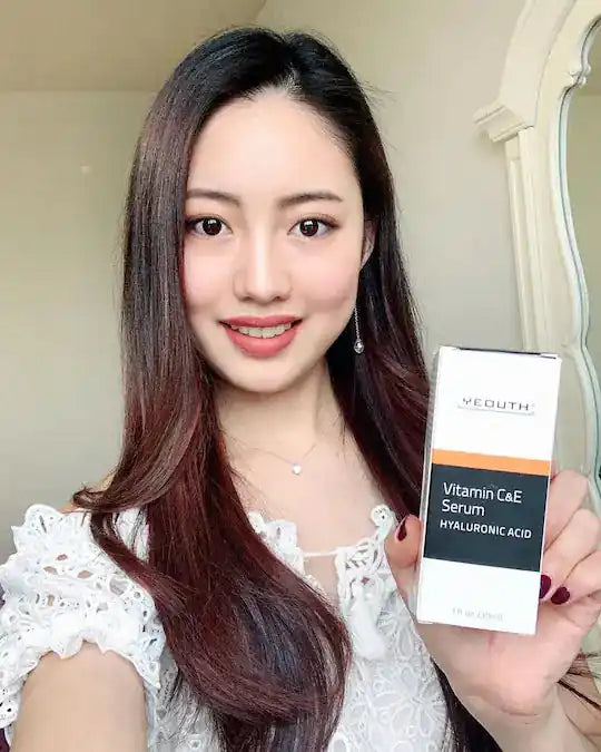 Woman holding a Vouth Vitamin C&E Serum with Hyaluronic Acid packaging.