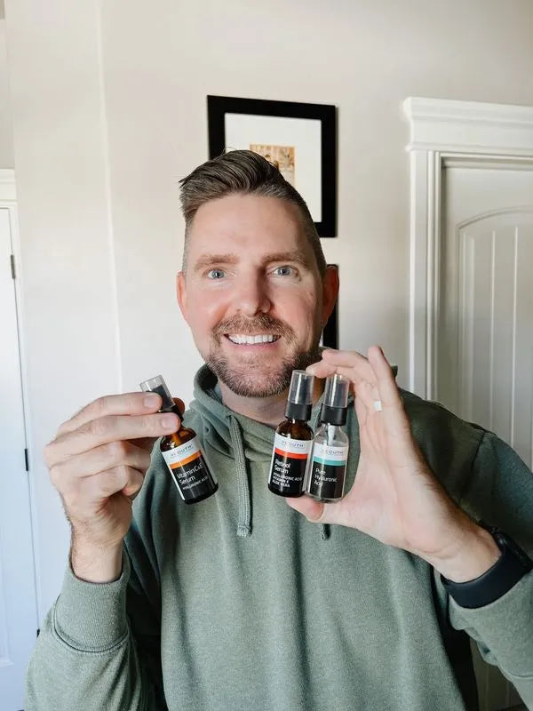 Face Serum Set Man smiling while holding three YEOUTH skincare serums: Vitamin C&amp;E Serum, Retinol Serum, and Pure Hyaluronic Acid.